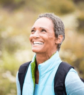 smiling senior woman with backpack hiking outdoors
