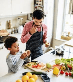 African American father and young son cooking together in kitchen